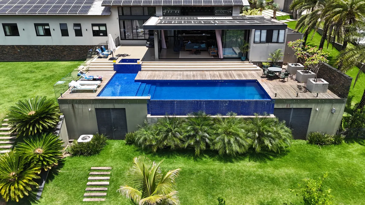 Residência com deck e piscina apoiados sobre estrutura em concreto, vista aérea